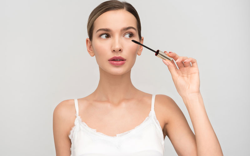 Mujer aplicando rimmel en los ojos
