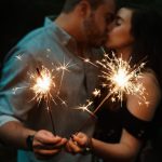 Pareja besándose mientras sostienen bengalas